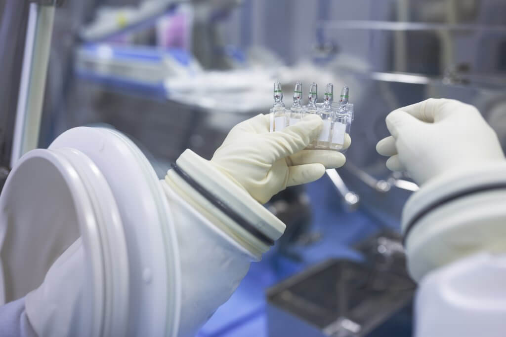 Scientist holding vials in insulator laboratory